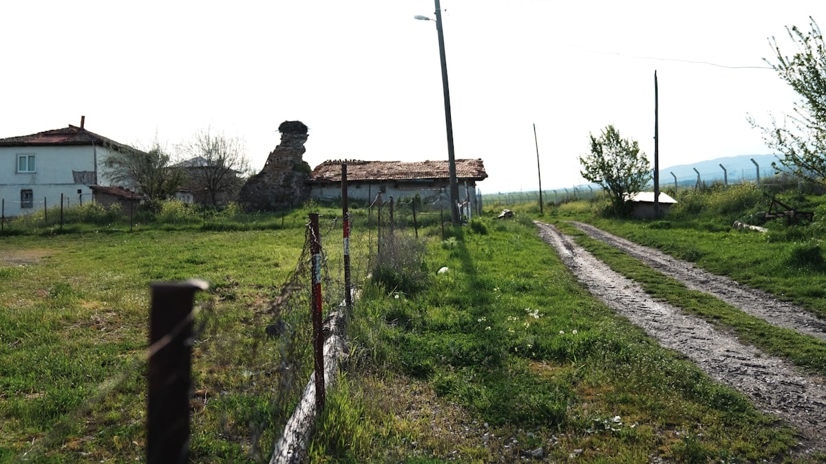a fenced in field with a house in the background
